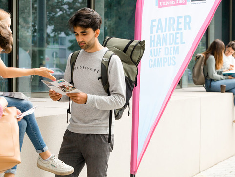 Student mit Flyer vor einer Universität (Bild: Fairtrade Deutschland / verenafotografiert)